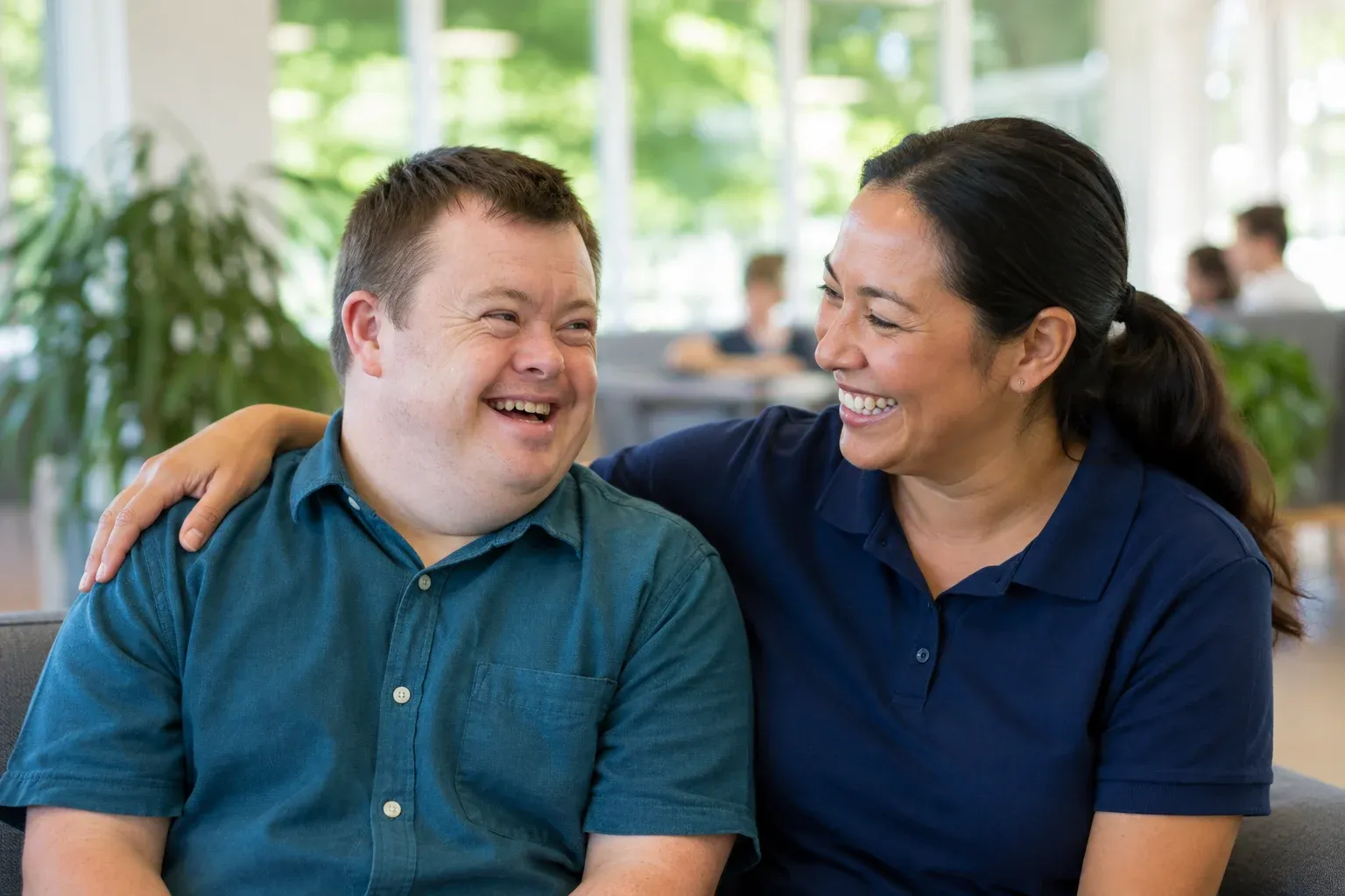 A participant and a support worker sharing a laugh in a bright community space